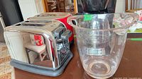 Chrome Hamilton Beach toaster, red KitchenAid toaster, clear plastic ice bucket foreground