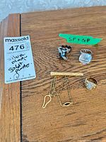 Overview of three rings and gold-tone tie bar on table