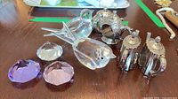 Group view of two crystal birds, three faceted gems and three silver teapot napkin rings