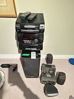Entire stereo stack on top of subwoofer with remotes, speakers, cable