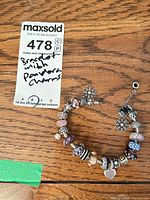Full bracelet laid flat with charms visible and lot tag