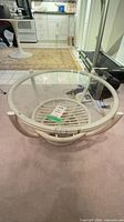 Full view of circular rattan coffee table with glass top