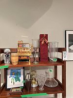 Shelf showing novelty slot machine, candleholder (not listed), fluted crystal vase, red gift box, and lower shelf with framed art, shaker, bowl, decanter