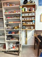 Full view of two shelving units with tools, jars of hardware, spray cans