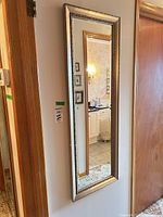 Full view of the vertical gold framed mirror on wall