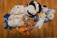 Group of eight assorted plush toys on wooden surface