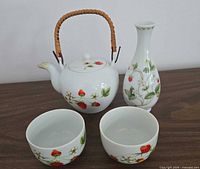 Group shot of teapot, two bowls, bud vase showing strawberry design