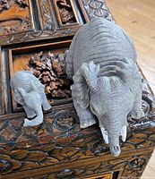 Adult and calf elephant figurines positioned side by side on carved wood surface