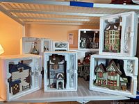 All eight Dicken’s Village buildings in Styrofoam inserts on shelving