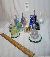 Group shot showing all 12 Fenton bells and 1 Partylite snuffer with ruler for scale