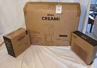 Three unopened Ninja product boxes: CREAMi appliance, 4-pack pints, dehydrating rack