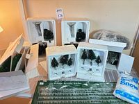 Lot overview showing snow-covered trees in styrofoam trays, bottlebrush trees, acrylic icicles package and plastic snow bag