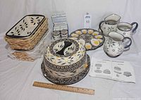 Group shot of entire lot showing loaf pans in baskets, Bundt cake set, deviled egg platter, pitchers, bowls, egg coddlers and ruler for scale