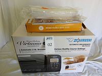Breadmaker boxed with slicer atop, sealed packaging visible