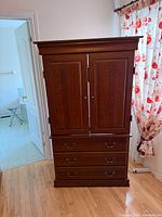 Front view of cherry-tone wood armoire entertainment unit