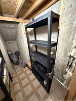 Front view of black plastic 4-tier shelving showing overall condition