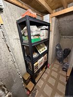 Full frontal view of black plastic 4-tier shelving unit in storage area