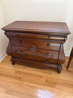 Front angled view of Bombe chest showing three drawers and carved motif