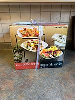 Front view of sealed boxed 3-tiered buffet server showing product image and item number