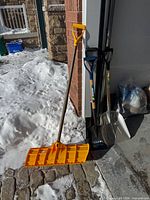 All four shovels leaning against garage wall