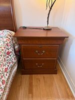 Front view of one nightstand beside bed, showing two drawers and hardware