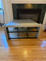 Front view of TV stand showing two glass shelves and top surface