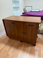 Front view of wooden sewing cart on wheels, drop leaf folded