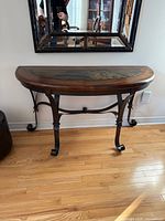 Front view of console table showing demi-lune shape, wood top, tile inlay, metal base