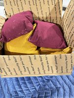 Box containing maroon and mustard yellow bean bags
