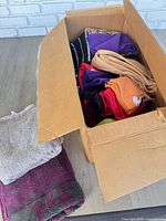 Cardboard box of mixed towels and linens on floor