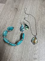Overview of bracelet, earrings pair, and pendant necklace on wood surface