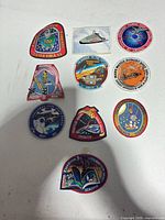 Overview of all ten embroidered space mission patches laid out on table