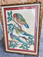 Full view of framed silk bird artwork leaning against wall