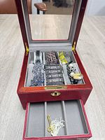 Overall view of open red jewelry case showing all six bracelets in top compartment and pull-out drawer below