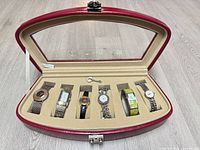 Open red watch case showing six watches and key