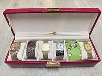 Overview of six wristwatches inside red watch case