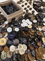 Wide shot of mixed loose buttons and some on cards, various colors and sizes visible