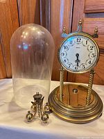 Clock with base, detached pendulum and glass dome