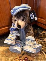 Front view of wolf plush with hat, scarf, boots, swing tag visible