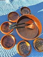 Entire set laid out: large bowl, six small bowls with carved fruit motif, two utensils