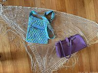 All three items laid out: purple handbag, quilted shoulder bag, cream lace shawl