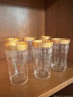 Full set of six clear tumblers with gold rims on shelf