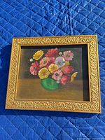 Full view of framed painting on blue quilt