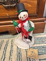 Full view of Annalee snowman doll on stand showing attire, cane, and tag