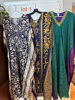 Three caftans hanging on hangers showing full designs