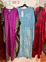 Front view of three caftans on hangers