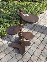Full view of wooden 4-tier paddle plant stand on stone patio