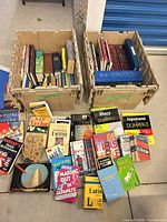 Overall view showing two crates filled with books and additional books laid out in front