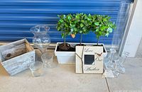 Group shot showing all items: two glass vases, three candlesticks, wood planter, picture, metal planter with artificial plants