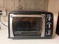 Front view of Bravetti toaster oven showing glass door, handle, and brand badge